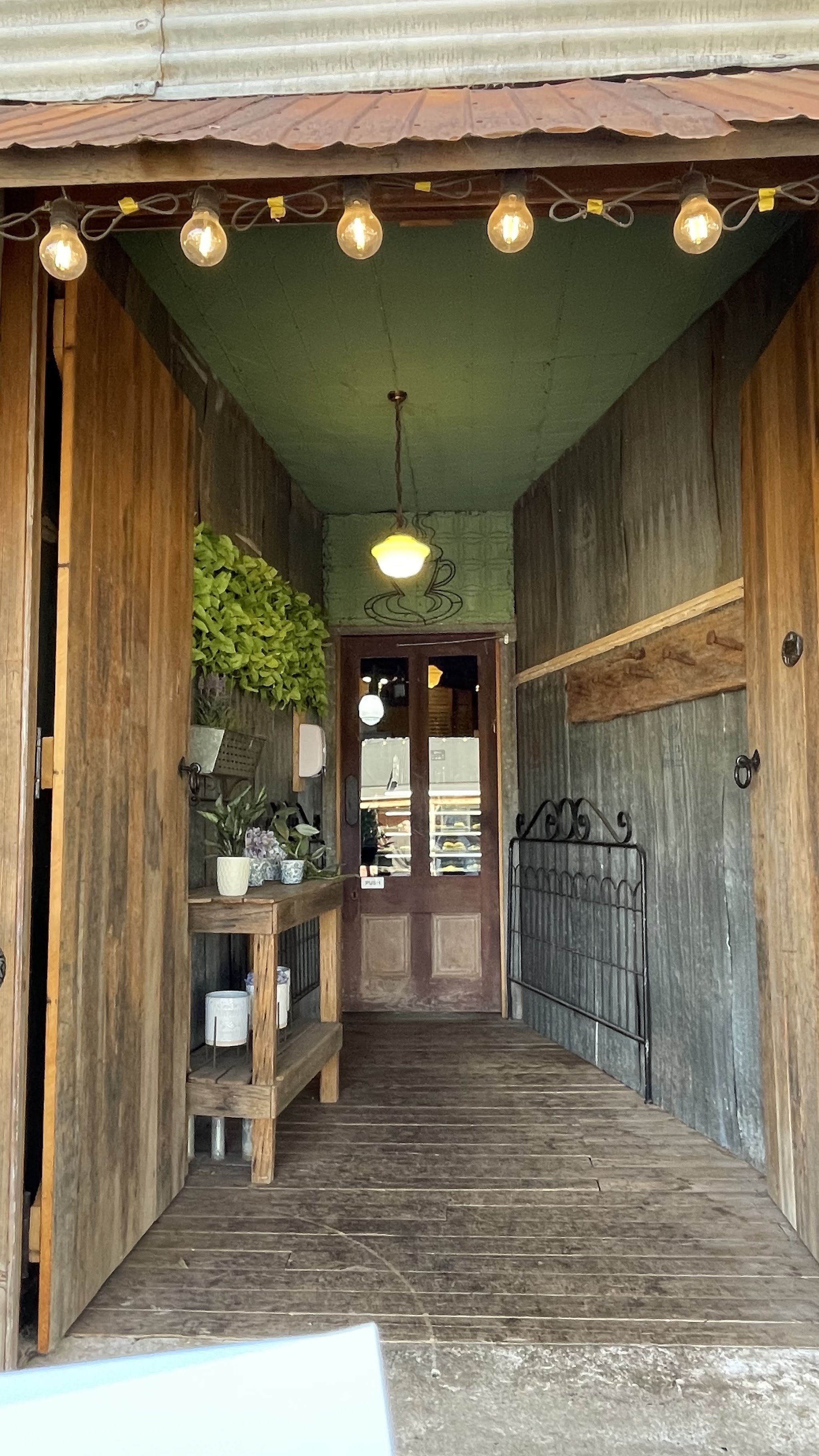 The covered entrance walkway with fairy lights, hanging plants and a stained-glass door