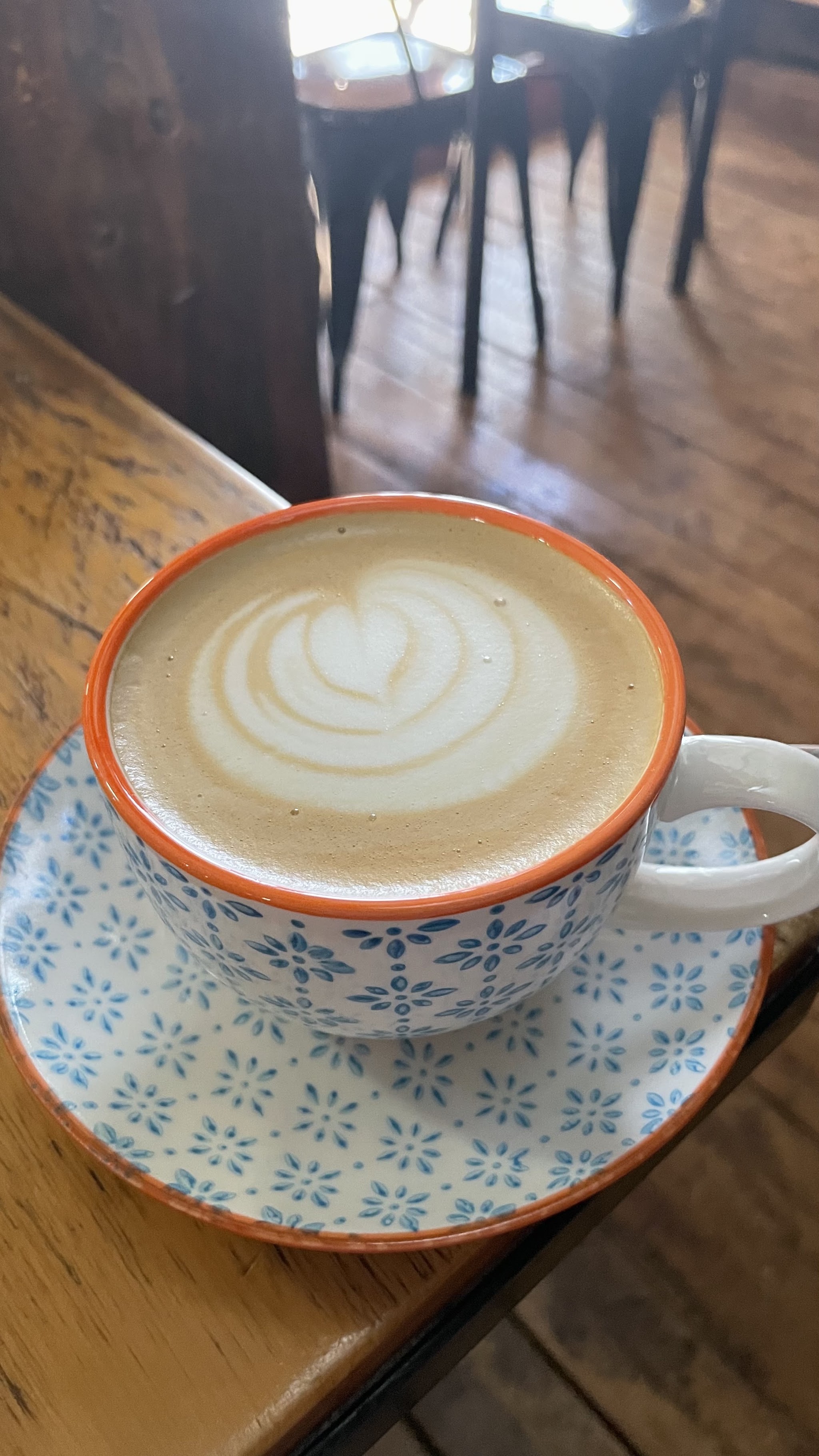 A flat white with latte art in a floral blue and white cup
