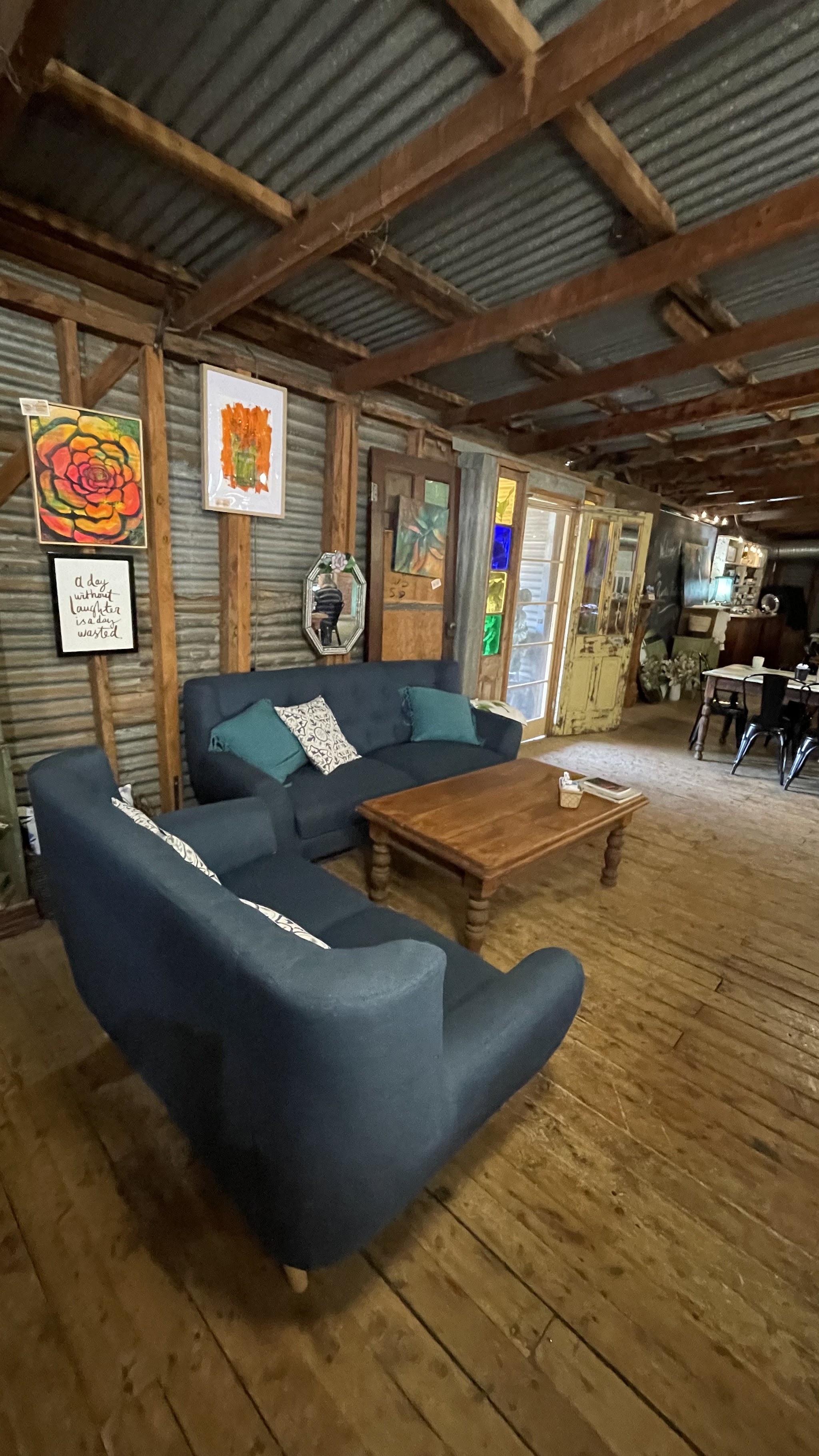 A lounge nook with navy sofas and local artwork on the corrugated-iron wall